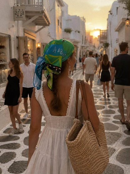 Κοπέλα κάνει βόλτα στα Ματογιάννια φορώντας ένα πράσινο πολύχρωμο μαντήλι ως μπαντανα στα μαλλιά.