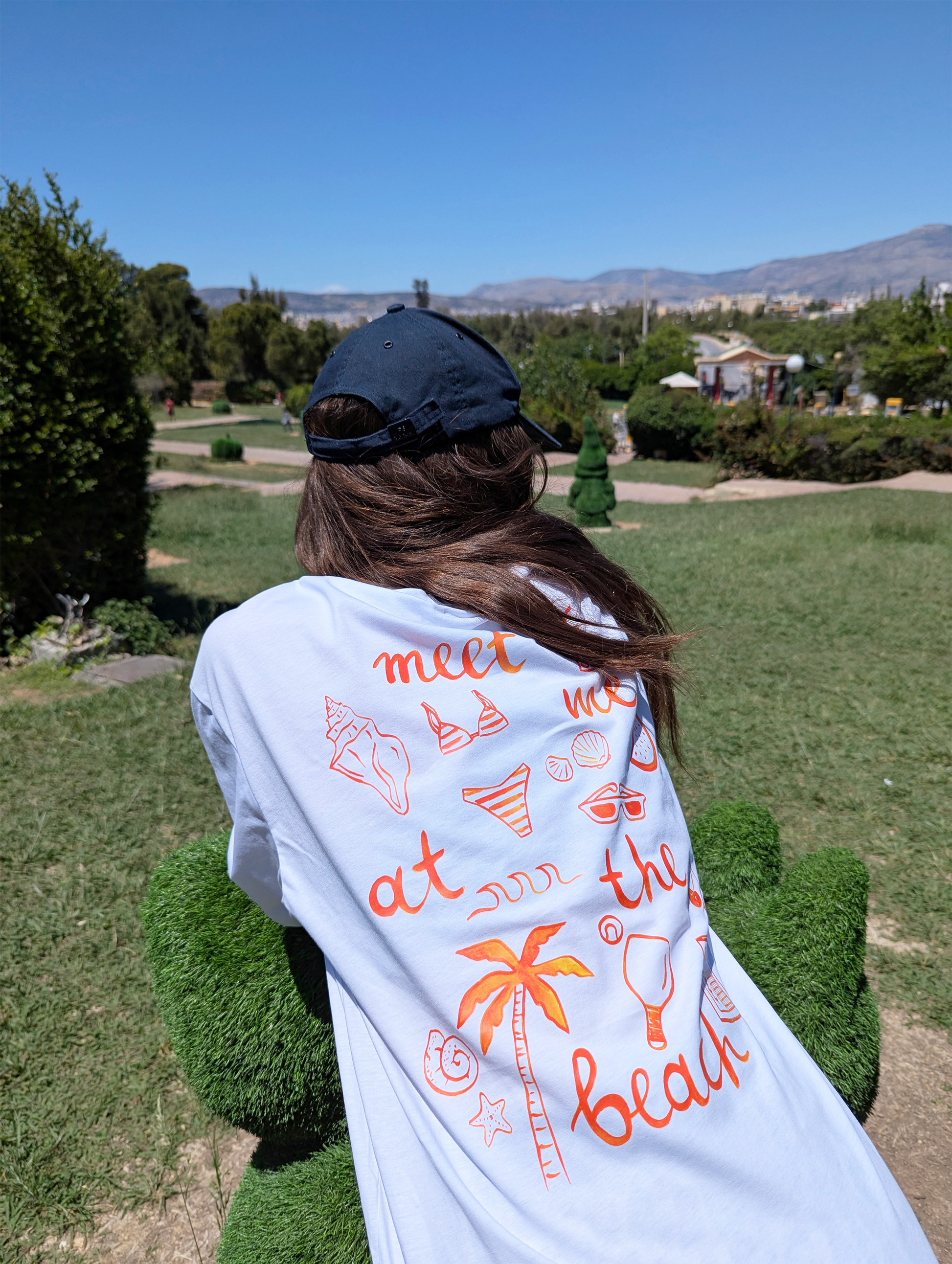 Πίσω όψη λευκού γυναικείου oversize T-shirt από βαμβάκι με τύπωμα ζωγραφισμένο στο χέρι Meet Me At The Beach

