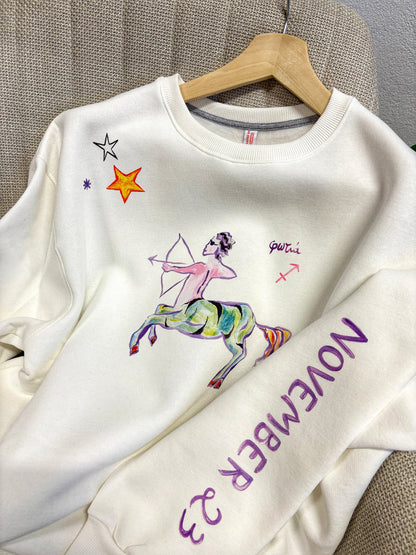 100% βαμβακερό φούτερ ελληνικής ραφής με πολύχρωμα τυπώματα μπροστά, πίσω και στα δύο μανίκια με θέμα το ζώδιο του Τοξότη.